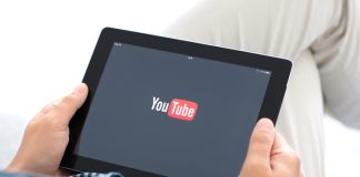 man holding iPad with app YouTube on the screen