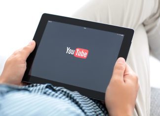 man holding iPad with app YouTube on the screen