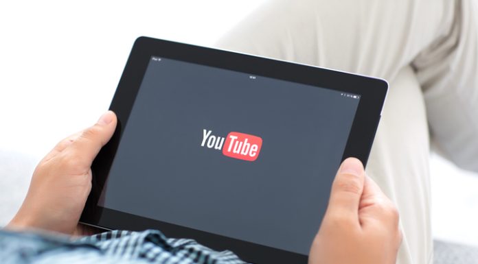 How to Buy YouTube Watch Hours & 1000 Subscribers man holding iPad with app YouTube on the screen