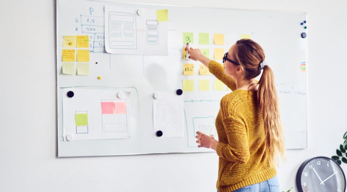 Back view of female web designer working on whiteboard in office