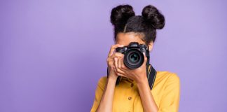Photo of amazing dark skin lady holding photo digicam in hands photographing foreign sightseeing abroad wear yellow shirt trousers isolated purple color background