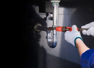 New Homeowner’s Guide to Plumbing Repairs Plumber fixing white sink pipe with adjustable wrench.