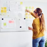 Back view of female web designer working on whiteboard in office