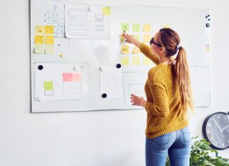 Back view of female web designer working on whiteboard in office