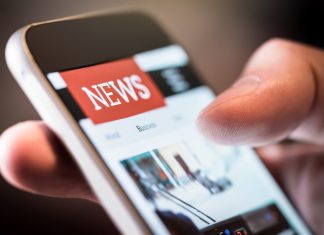 Online news in mobile phone. Close up of smartphone screen. Man reading articles in application. Hand holding smart device. Mockup website.