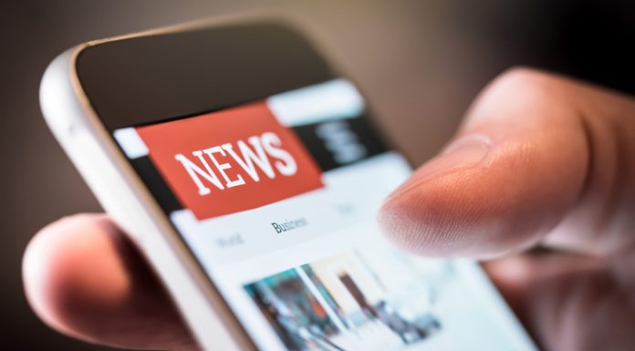 Newspaper as a Tech Business. Story of Bulletin Online news in mobile phone. Close up of smartphone screen. Man reading articles in application. Hand holding smart device. Mockup website.