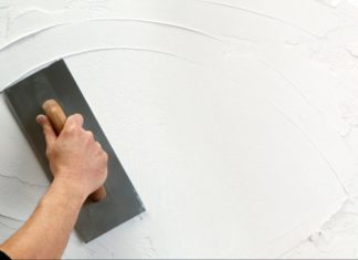 Plastering Cost UK : Skimming & Rendering Prices 2022 hand holding plastering tool