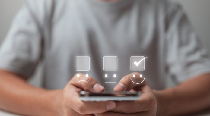 Stay Ahead in Competition by Choosing Outsourcing Mobile App Development Agency A businessman uses mobile app to make a smiling face on the touch screen.