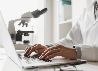 Scientist or student using laptop computer and microscope