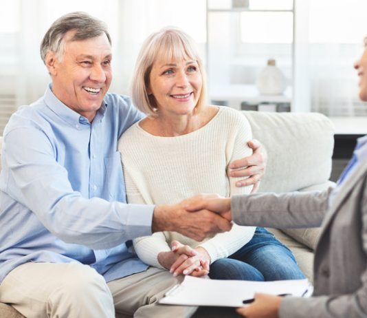 Female Real Estate Agent handshaking happy mature couple at home