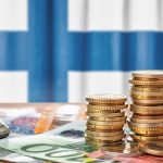 Euro banknotes and coins in front of the national flag of Finland