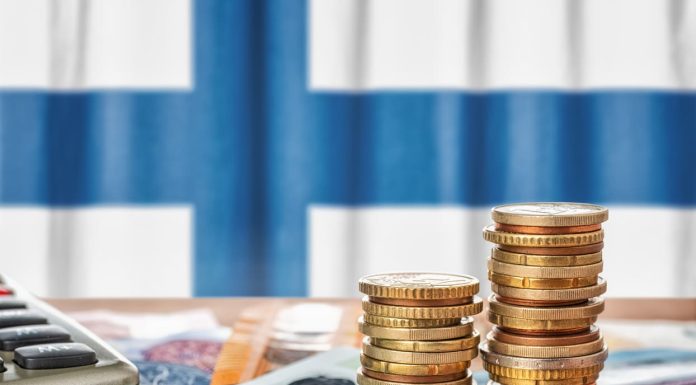 Euro banknotes and coins in front of the national flag of Finland