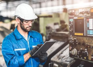 Engineer setup the CNC machine with G-Code programming upload from Computer Tablet for technology in heavy industry
