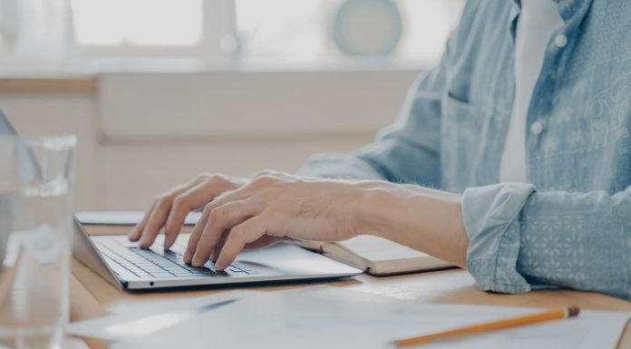 Close up image of male hands typing on laptop keyboard