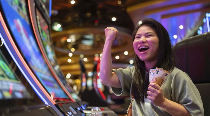 exited asia female woman slot machine gambling cheerful smile hand pressing bet button in casino club entertainment concept,exited asian woman hand play slot machine in casino hotel