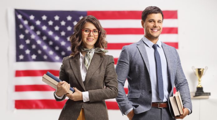 Young man and woman holding books in front of USA flag