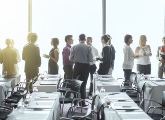 10 Surefire Ways To Increase Event Registration Group of people standing by windows of conference room, socializing during coffee break