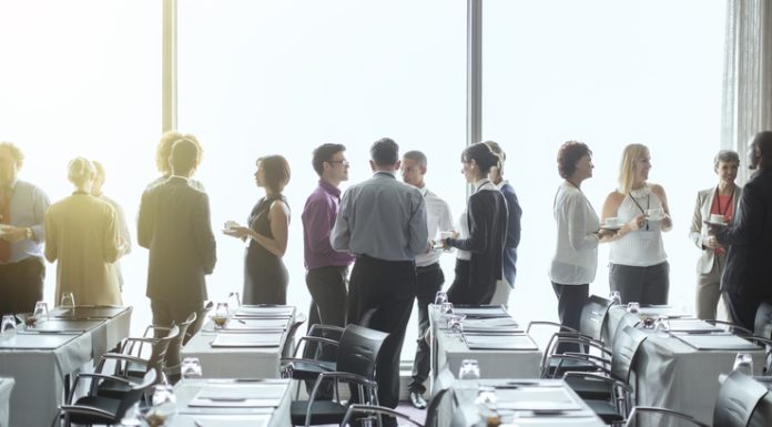 10 Surefire Ways To Increase Event Registration Group of people standing by windows of conference room, socializing during coffee break