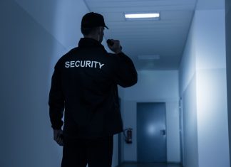 The Role of Security Guards in Ensuring Safety and Security Security Guard With Flashlight In Building Corridor