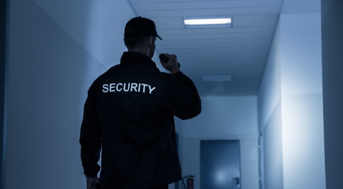 The Role of Security Guards in Ensuring Safety and Security Security Guard With Flashlight In Building Corridor