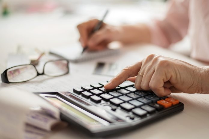 Pension calculation concept, old hands counting finances on a home calculator , close- up Pension calculation concept, old hands counting finances on a home calculator , close- up