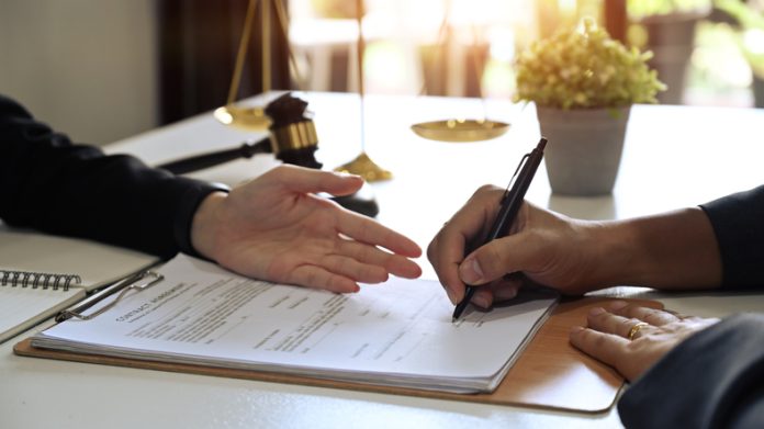 Young businessman signing agreement with skilled lawyer and showing place for signature on contract document. Hire A UK Immigration Lawyer