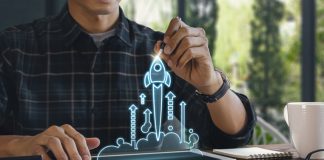 Business start up, start, new project or new idea concept. Wooden blocks with launching rocket graphic arranged in pyramid shape and a man is holding the top one.