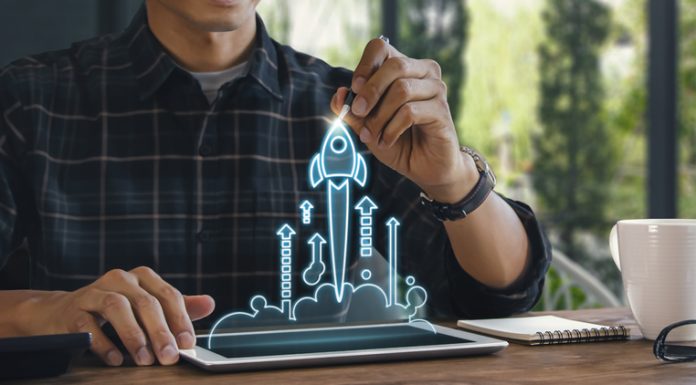 The Magic Spark Model: Learning to Innovate Business start up, start, new project or new idea concept. Wooden blocks with launching rocket graphic arranged in pyramid shape and a man is holding the top one.
