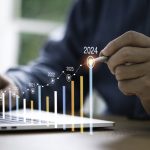 In 2024 Work on the Business, Not in the Business Businessman use electronic pen writing rising colorful graph from 2023 to 2024 year of business planing and stock investment growth concept.