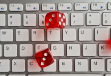 Red dice lying on white keyboard as online casino concept