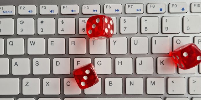 Red dice lying on white keyboard as online casino concept