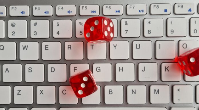 Red dice lying on white keyboard as online casino concept