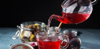 A Guide to Choosing the Best Loose Leaf Tea for You Process brewing tea, tea ceremony, Cup of freshly brewed fruit and herbal tea, dark mood. Hot water is poured from the kettle into a cup with tea leaves.