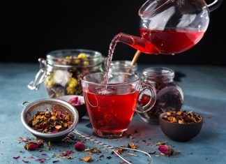 Process brewing tea, tea ceremony, Cup of freshly brewed fruit and herbal tea, dark mood. Hot water is poured from the kettle into a cup with tea leaves.