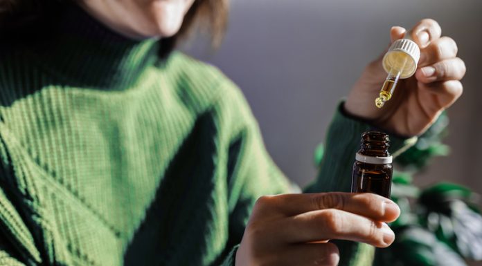 Managing Pain Naturally: The Impact of CBD Oil on Pain Relief Woman holding a dropper of sublingual cbd cannabis hemp oil - Alternative medical treatment