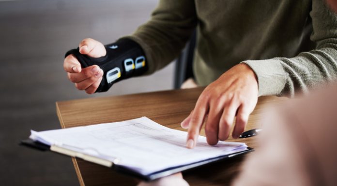 Injury, compensation and man hands with insurance documents, legal contract and paperwork. Disability, accident and people in lawyer or attorney meeting for advice, agreement or policy report closeup