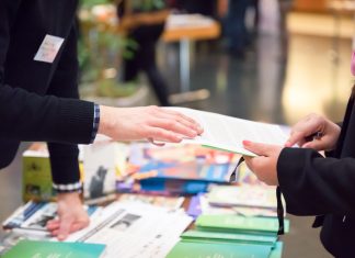 Designing Flyers That Convert: Tips for Creating Compelling Calls to Action Man and Woman Sharing Information Leaflet over Exhibition Stand