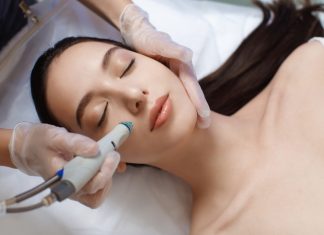 Professional female cosmetologist doing Hydradermabrasian procedure in Cosmetology clinic.