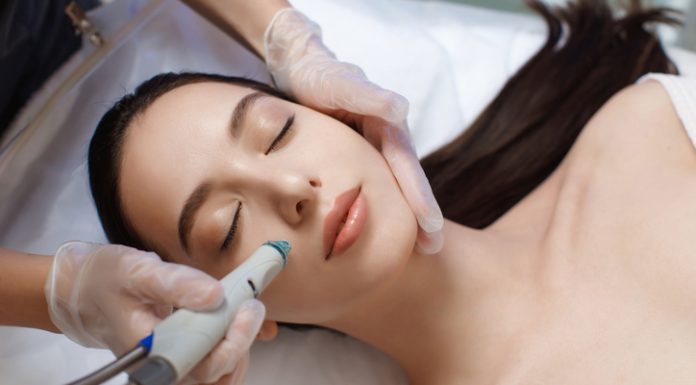 Professional female cosmetologist doing Hydradermabrasian procedure in Cosmetology clinic.