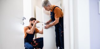 Locksmiths in London: A Guide to Trusted Services and Security Solutions Best men at work. Full length shot of two locksmith, repairmen, workers in uniform installing, working with house door lock using screwdriver.