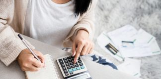 What is Not a Good Way to Prevent Unnecessary Spending woman writing a list of debt on notebook calculating her expenses with calculator