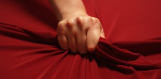 The Path to Ecstasy: A Journey into Understanding Women’s Orgasms woman hand squeezes the red sheet