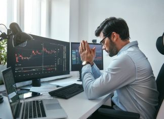 businessman holding palms together with data on monitors