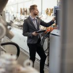 Achieving Cost Reduction in Manufacturing: Strategies and Tools Business man checking quality on laptop in factory