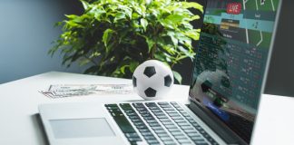 Corporate Governance and Personnel Policy in Leading Gambling Companies Close up cropped shot of white office desk with dollar banknotes and laptop with bookmaker's website interface on its screen