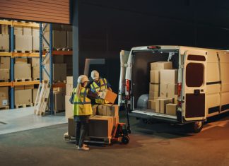 two people carrying boxes in front of the warehouse