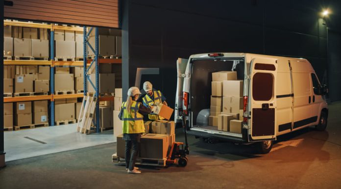 two people carrying boxes in front of the warehouse