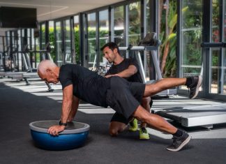 Personal trainer helping an old man in the gym