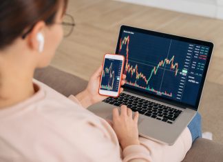 woman looking at financial stock market using cellphone and laptop