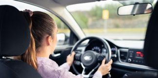 Driving Excellence: Choosing the Best Driving School in Vancouver for Confident and Skilled Drivers Woman driving car. Young driver. Testing vehicle in dealership or student training in school to get license. Hands on steering wheel. Behind back inside view of cockpit.